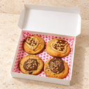 Quatre cookies dans une boîte entrouverte.webp